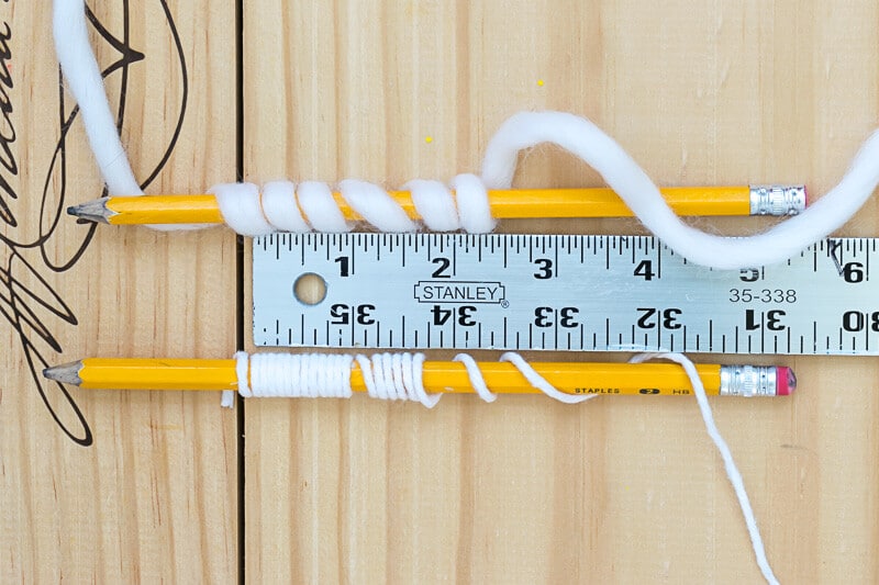 Yarn wrapped around a pencil against a ruler.