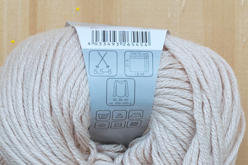Yarn label on a beige skein of yarn.