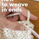 A hand showing how to weave in the ends of a knit project after binding off.