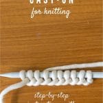 White Yarn cast on to knitting needles using the long-tail method.