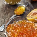 Jar of golden plum jam and a spoonful of jam with golden plums in the background.