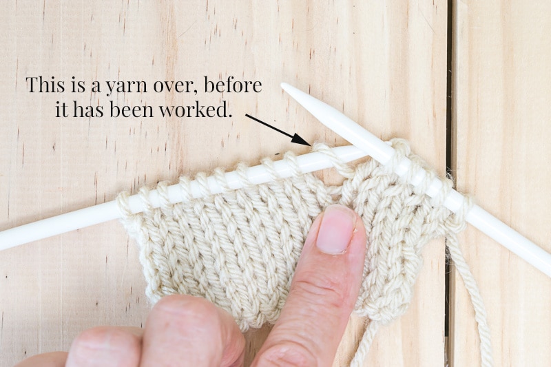 Knit fabric on needles and showing where an errant yarn over is. Addressing errant yarn overs immediately prevents you from having to fix holes in knitting later on.