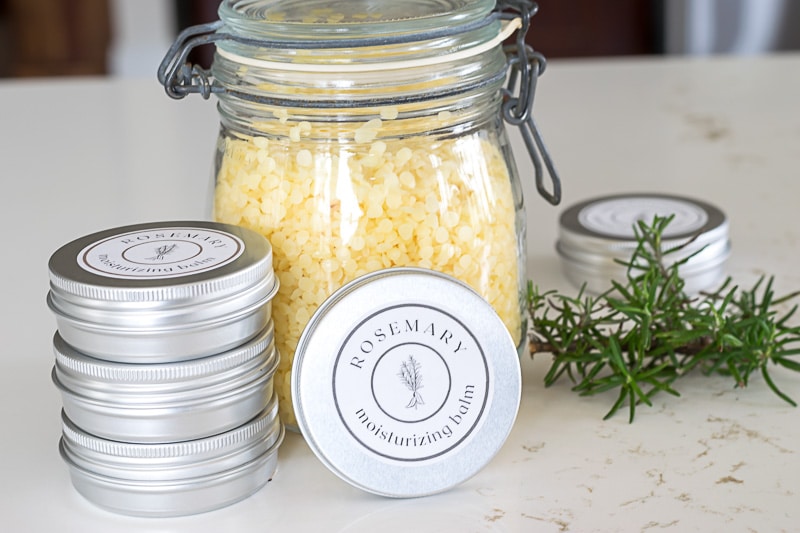 Beeswax pellets in a glass jar and tins of hand balm.