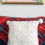 White Christmas Tree Pillow on blue sofa with red tartan blanket in the background.