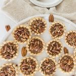 Overhead shot of pecan tartlets on a white plate.