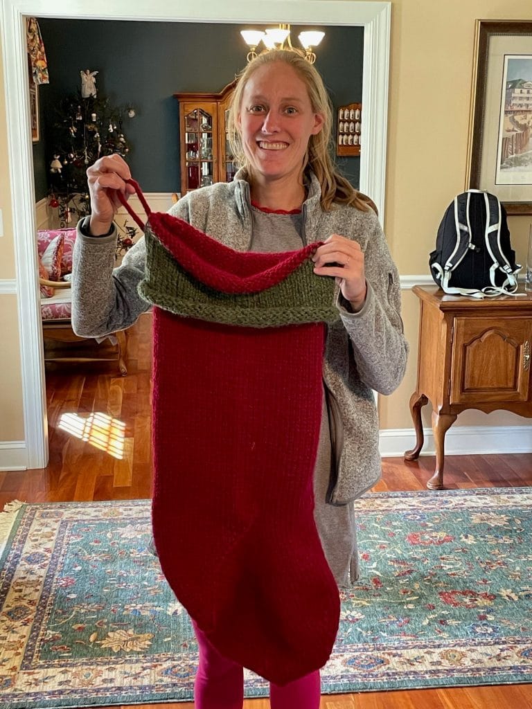 Woman holding large Red and green Christmas stocking.