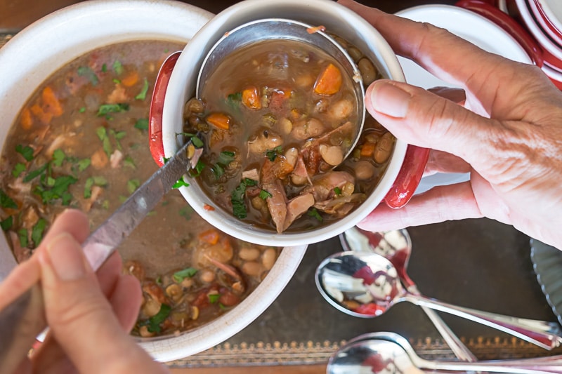 Ladling 15-Bean Soup into a soup bowl.