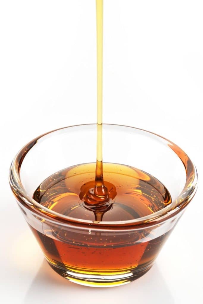 honey dripping into a glass jar.