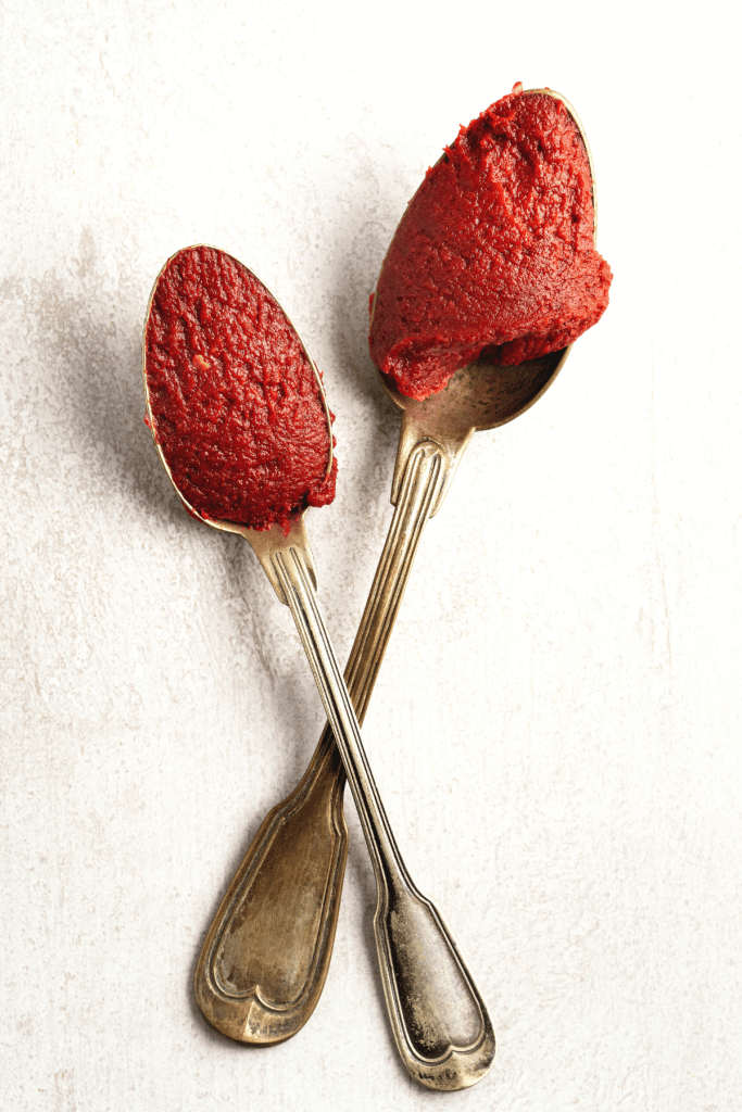 Two spoons with tomato paste.