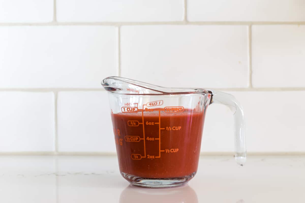 The measuring cup of tomato sauce.