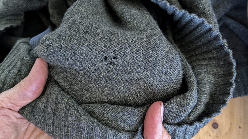 A grey sweater with moth holes.