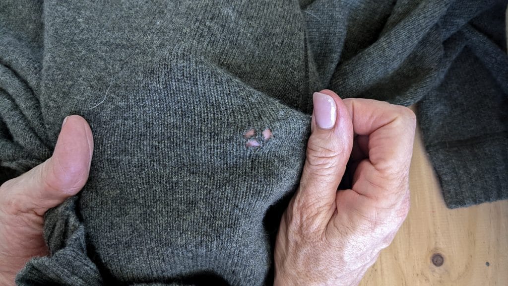 A hole in a sweater caused by a moth that eat clothes