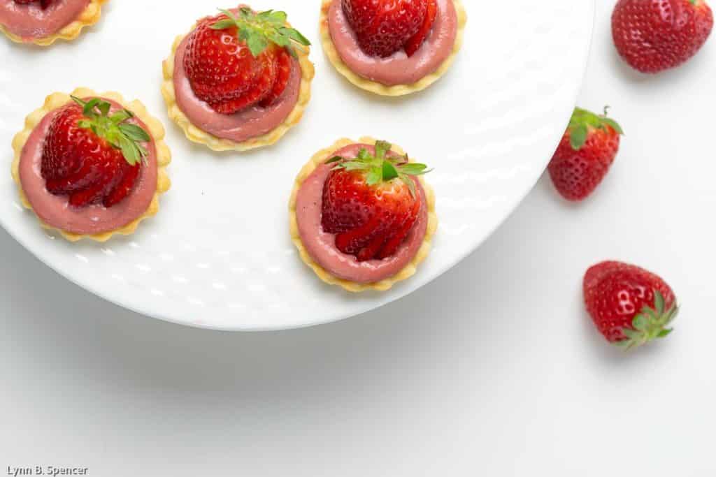 Mini strawberry curd tarts with fresh strawberries on top.