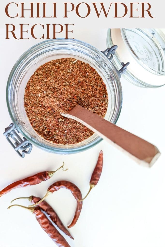 A jar of Smoky Chili Seasoning Recipe in a jar with chiles alongside.