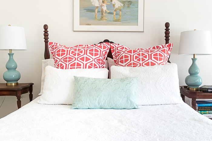Bed with orange and white pillow shams.