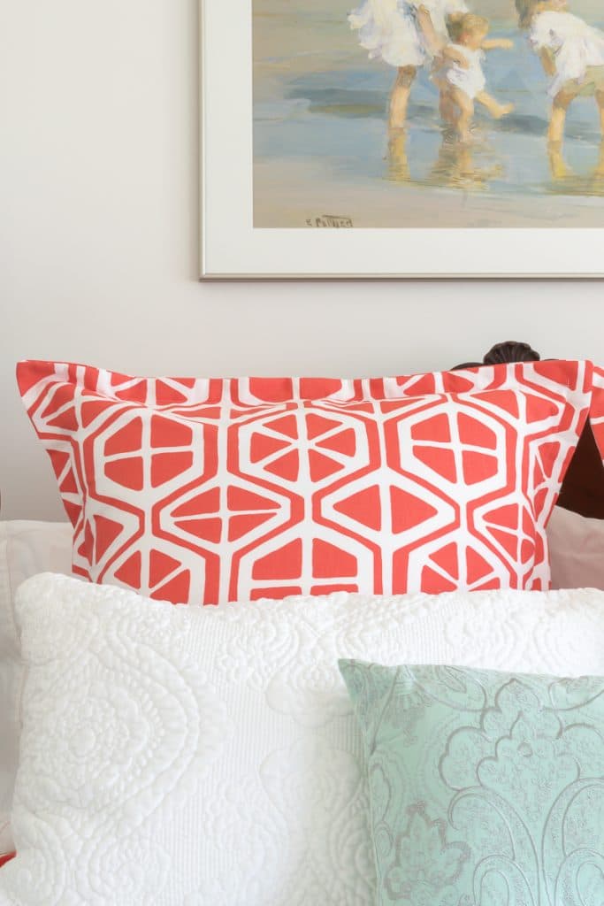 A n orange and white pillow on a bed