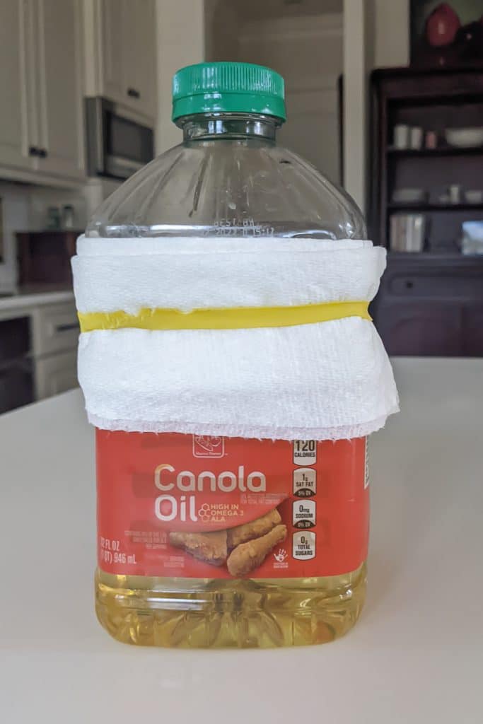 White paper towel wrapped around a bottle of oil held on with a rubber band.