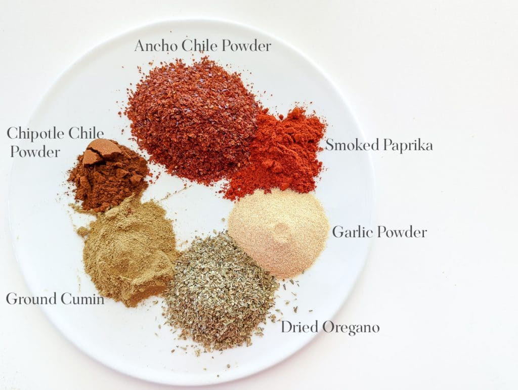 A plate with a variety of spices used to make chili seasoning.