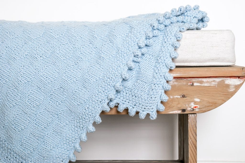 Blue baby blanket on a wooden bench.