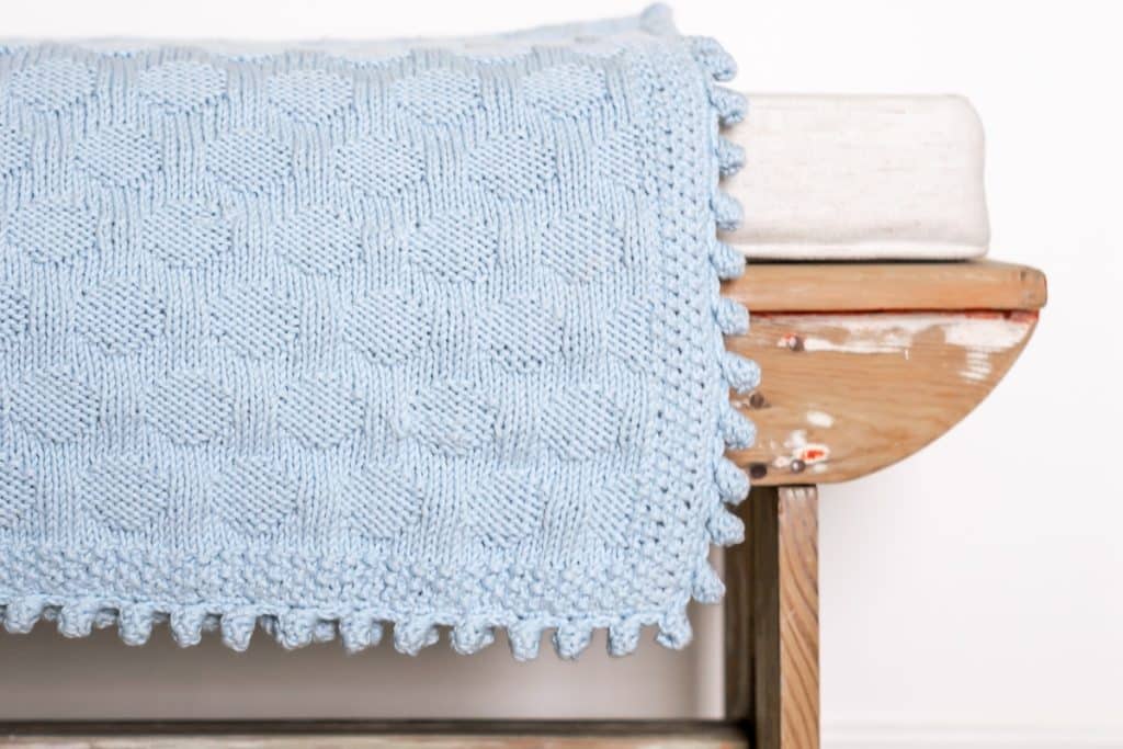 Blue baby blanket on a wooden bench.