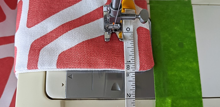 Sewing machine foot and tape measure on fabric.