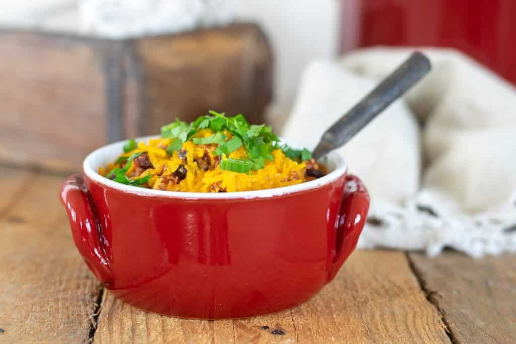 A red bowl of turkey chili with toppings.