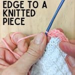 Hands holding crochet hook on knitted piece.