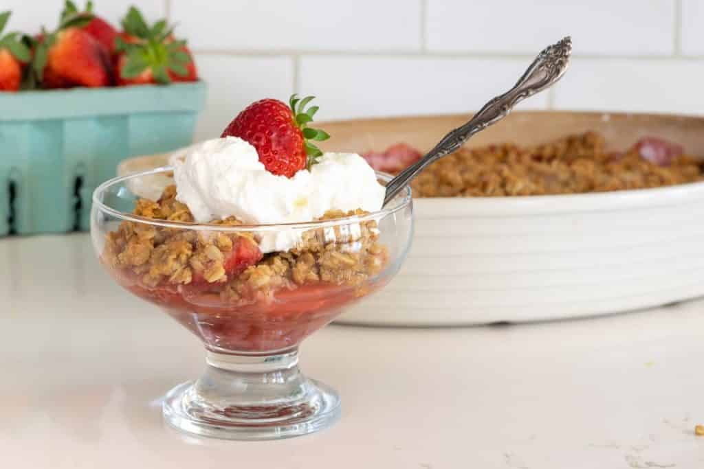 bowl of strawberry crisp with whipped cream and strawberry