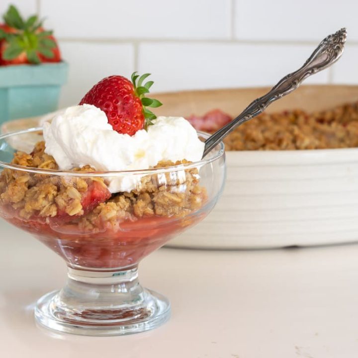 bowl of strawberry crisp with whipped cream and strawberry