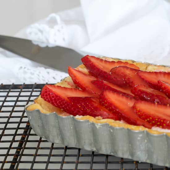 Strawberry Tart in tart pan on a cooling rack.