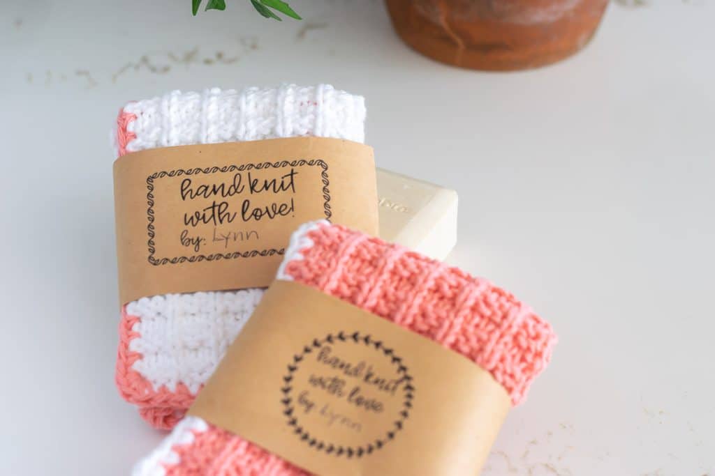 White and peach knit washcloths with brown kraft paper wraps around them.