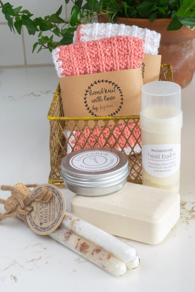 Peach washcloth in a gold mesh box with a bar of soap, a tin and a tube of heel balm in front.