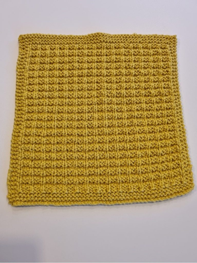 A close up of a mustard colored dishcloth