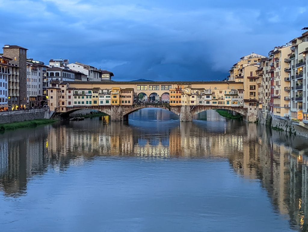 Ponte Vecchio over a body of water with a city in the background