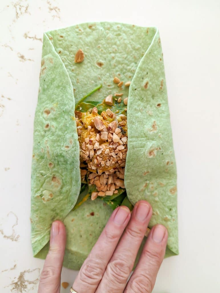 Folding the sides of a Curried chicken salad wrap