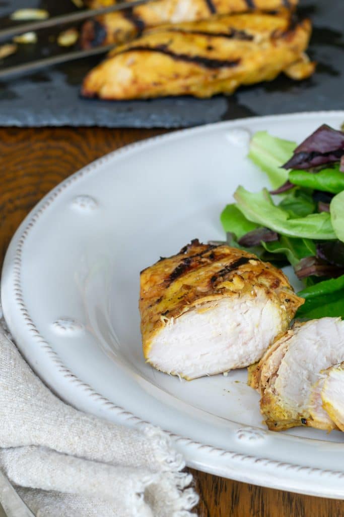 Sliced chicken on a plate with greens