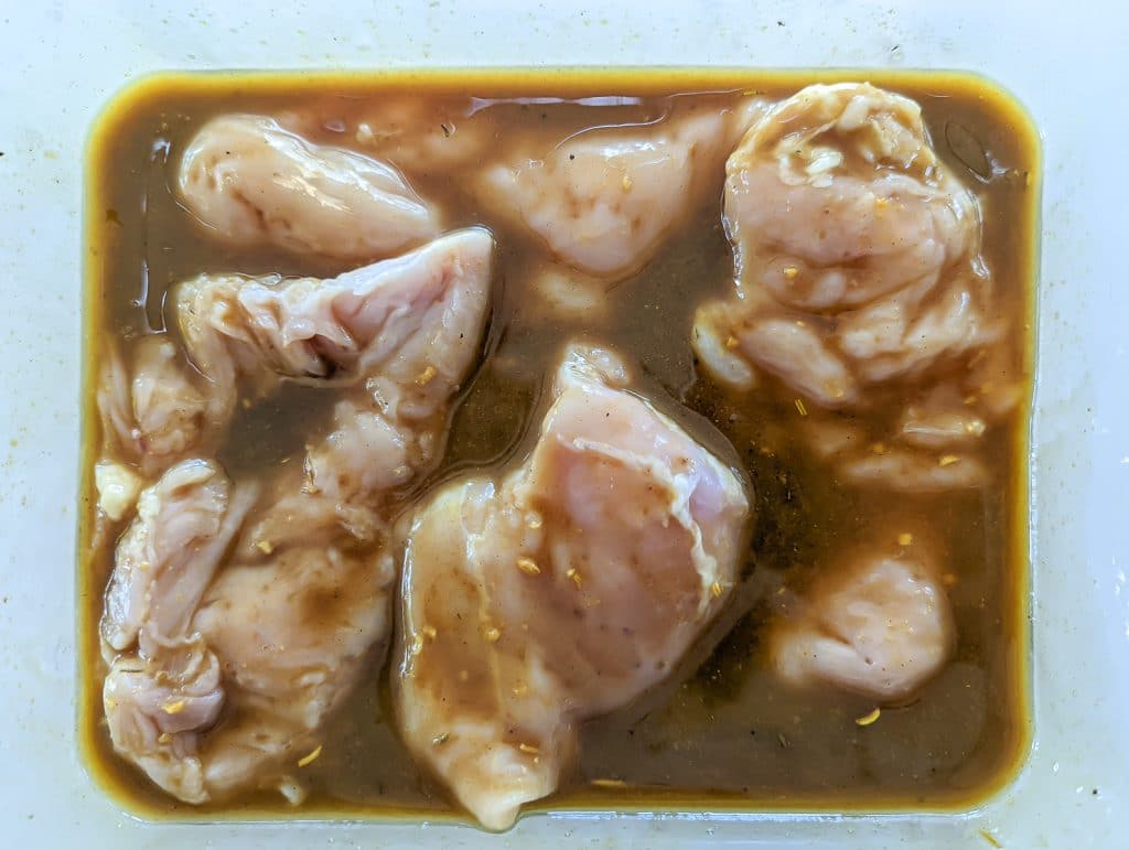 Marinating chicken in glass container.