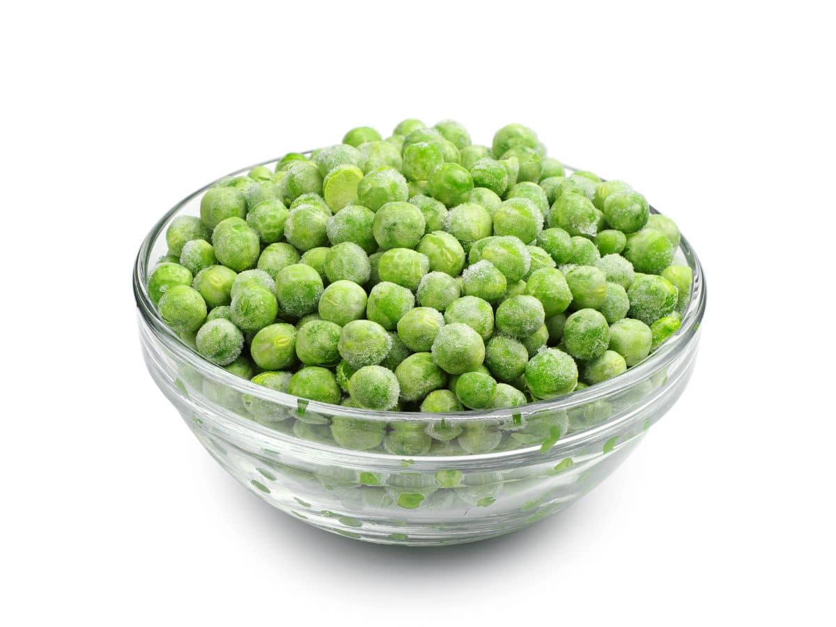 FRozen peas in a glass bowl, a more economical and healthy way to purchase peas.