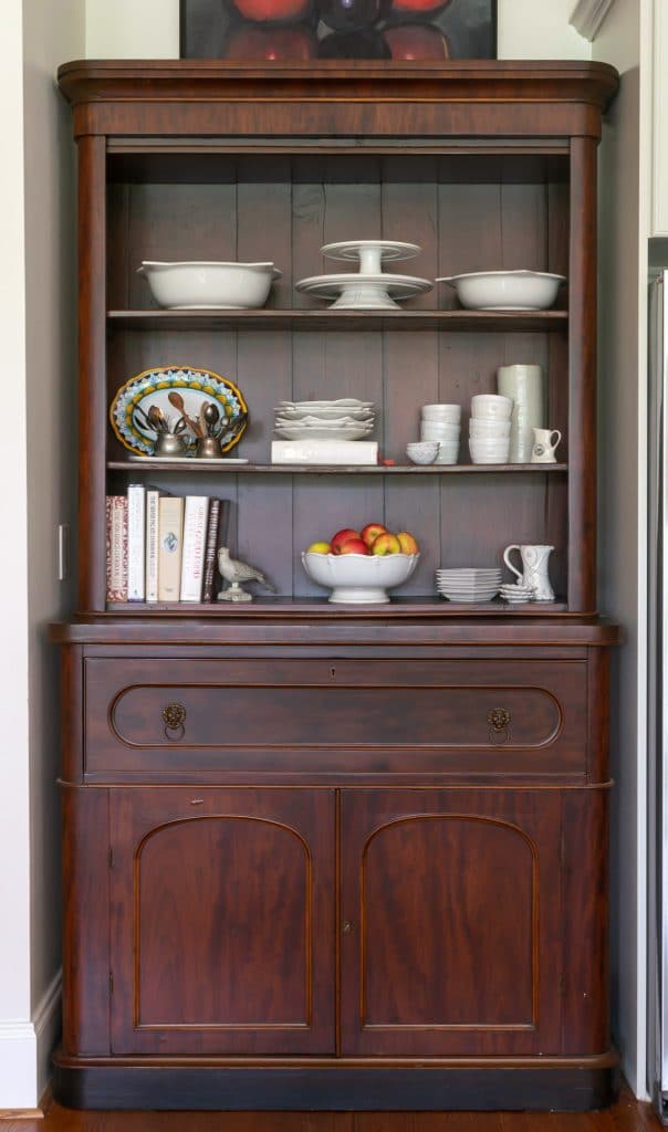 Wooden hutch with white dishes and cookbooks.