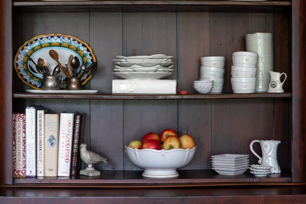 A kitchen hutch decorate with plates and cookbooks.
