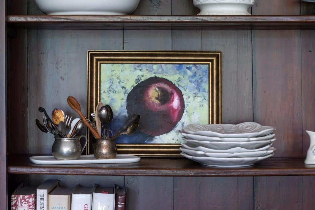 Apple painting on hutch with white dishes