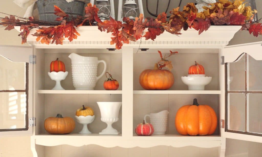 Hutch with white vases and orange pumpkins