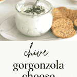 Jar of Gorgonzola Cheese Spread with a knife on a plate of crackers.