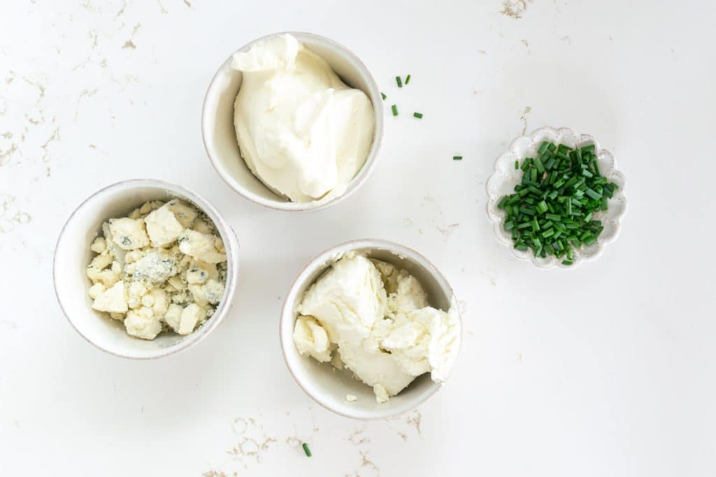 Overhead shot of goat cheese, gorgonzola, cream cheese and chives.