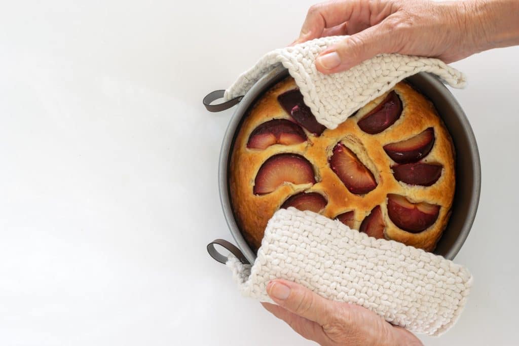 Plum cake held with two potholders.