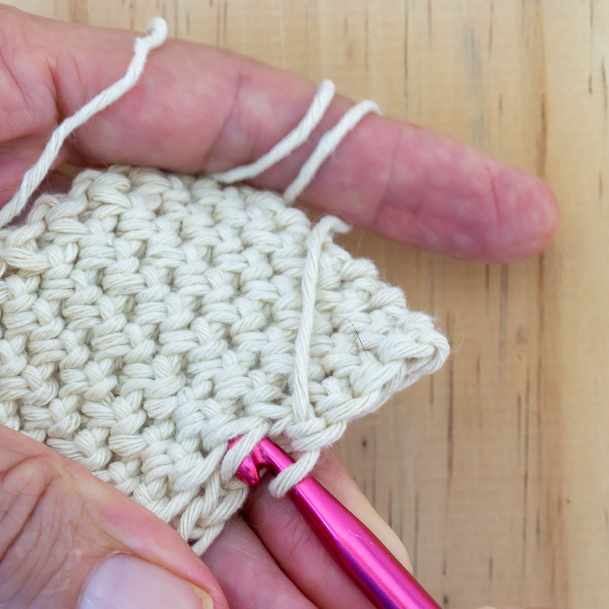 Pushing crochet hook through fabric.