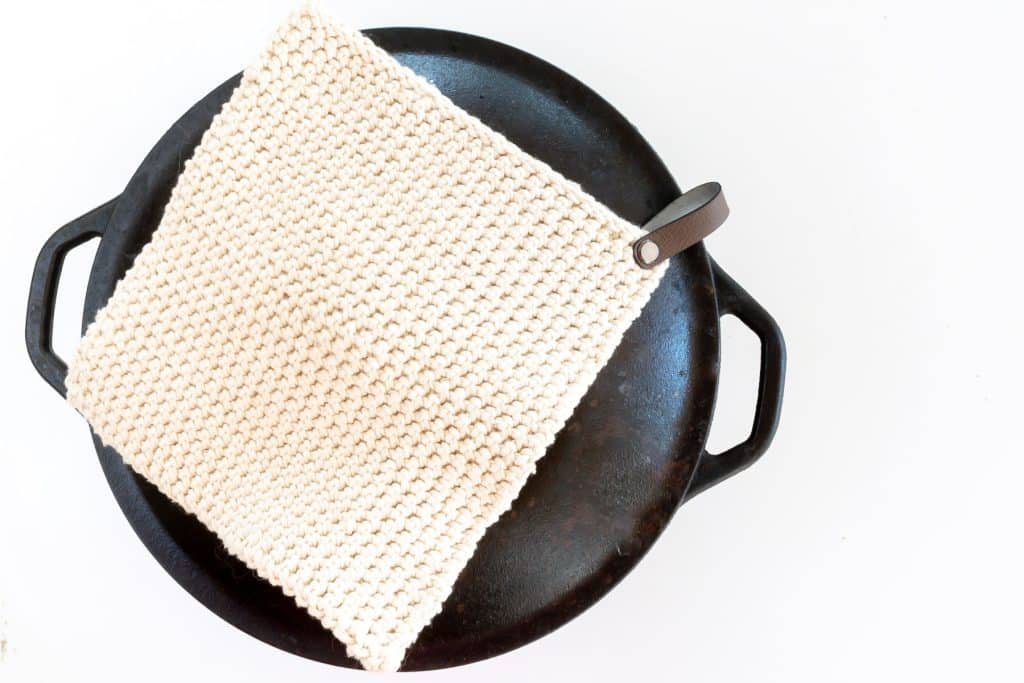 Crochet potholder on black cast iron pot.