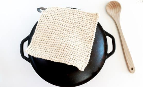 Overhead shot of Crochet Potholder on a black pot with a wooden spoon.