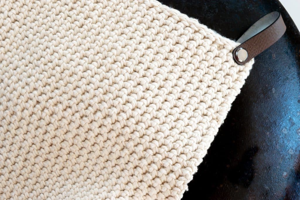 Crochet potholder on black cast iron pot.