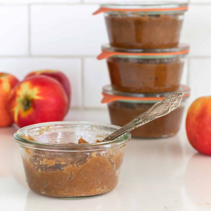Jars of apple butter with fresh apples.